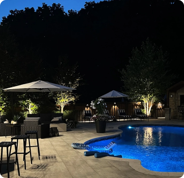 Outdoor spot lighting illuminating trees and pool area at a backyard home in the GTA